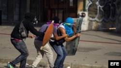 Un grupo de manifestantes se defienden de la policía durante una protesta en Venezuela.