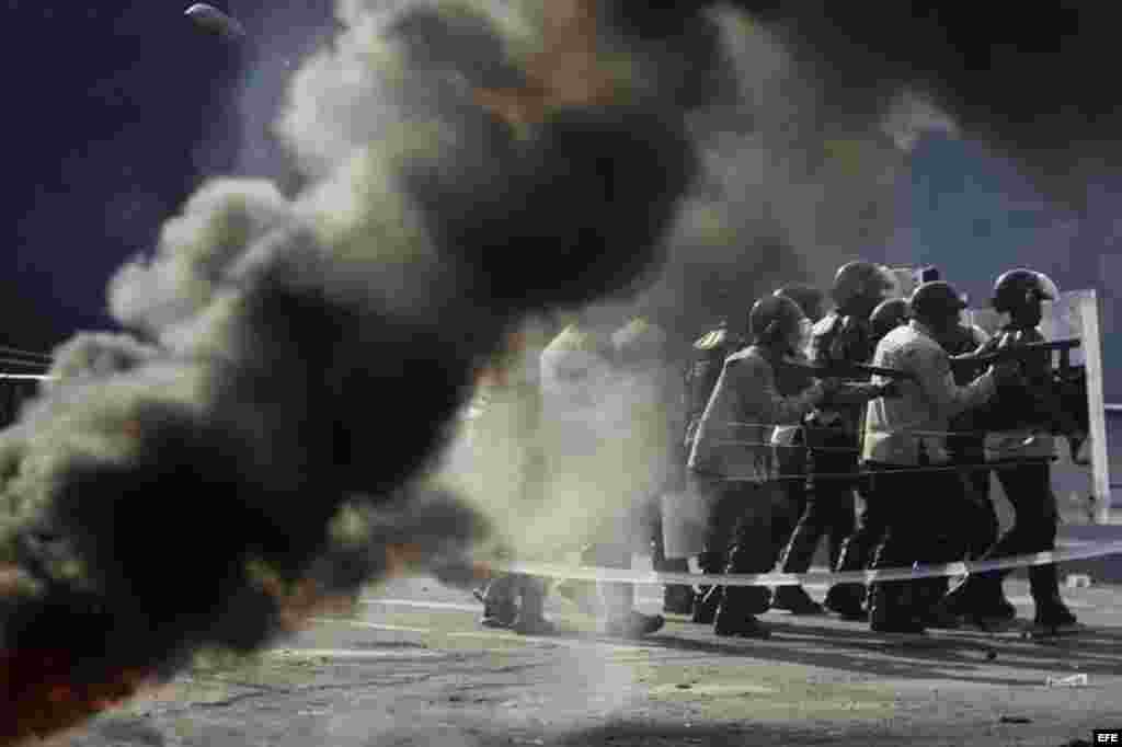 Un grupo de manifestantes se defienden de la policía durante una protesta