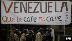 Un grupo de manifestantes se defienden de la policía durante una protesta