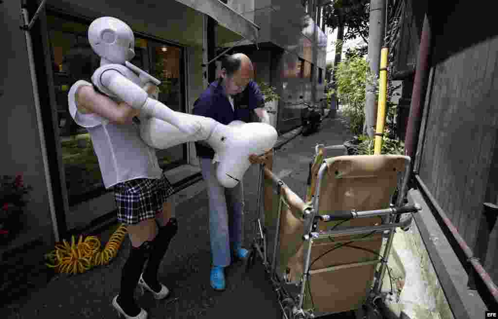 Tomomi Ota (i) y su padre Norio colocan a Pepper en un carrito para pasearle por Tokio. 